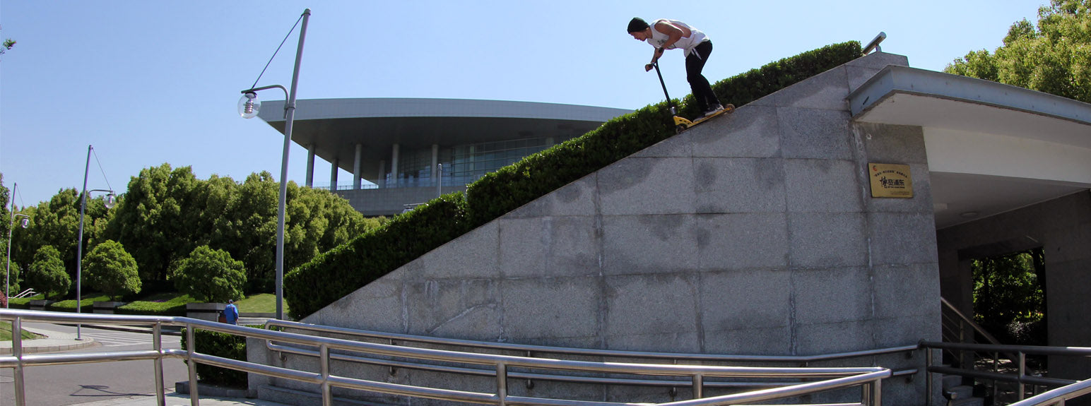 Man riding a Madd Gear pro stunt scooter down a slope.